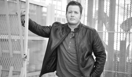 Chaz Bono in a black leather jacket poses for a picture.